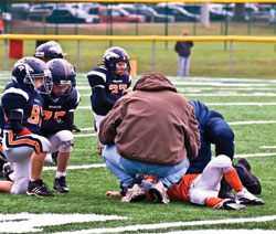 A young player down after a tackle on the field during a little league football game. &copy; Susan Leggett - Dreamstime.com