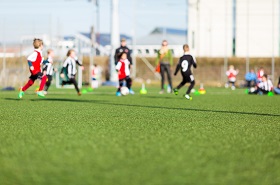 Children playing soccer on a green synthetic field.
