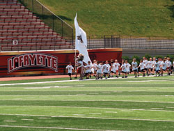 Young athletes running onto the field behind the college mascot for the last day of events at Lafayette College's 20th Annual Youth Football camp. &copy; Cynthia Farmer - Dreamstime.com