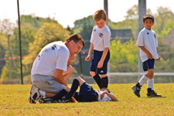 A player on the ground being checked by his coach during a regular season game in Forsyth County, Cumming Georgia. &copy; Susan Leggett - Dreamstime.com
