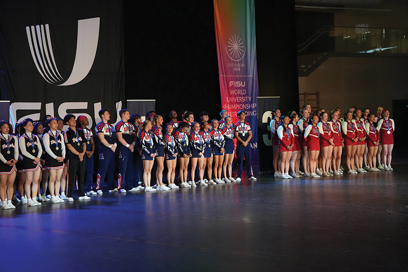 A diverse group of cheerleaders in USA uniforms smiles together for a photo.